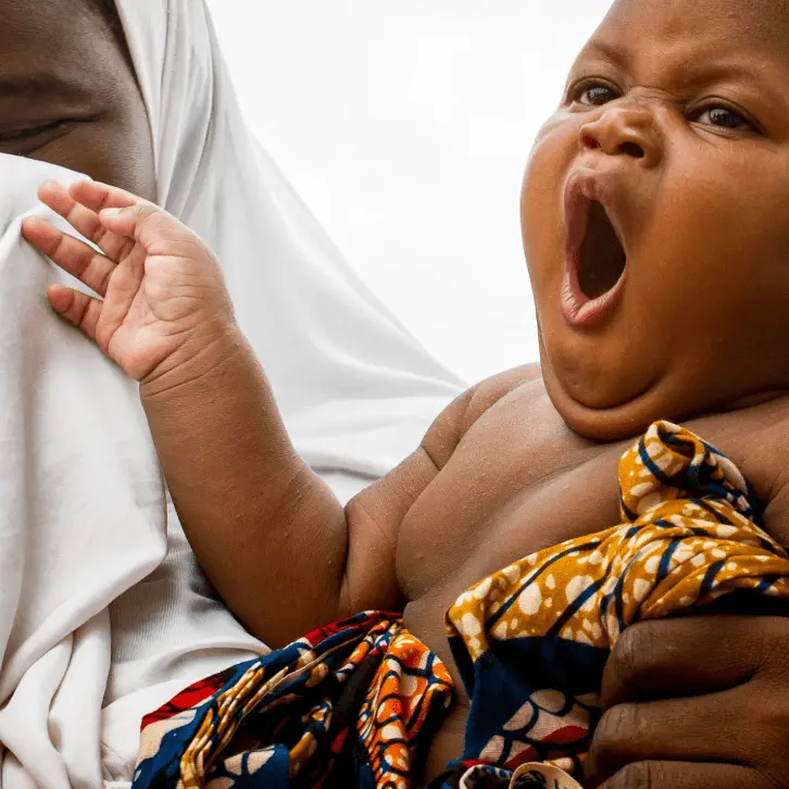 Now is better than before baby for portfolio page Infant yawning comfortably while sitting on mama's lap at a well baby clinic.