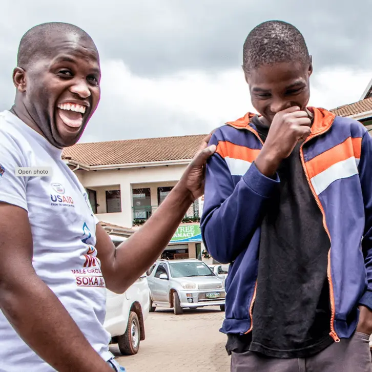 Circumsised photo for portfolio page Two African men laughing together outside a clinic.